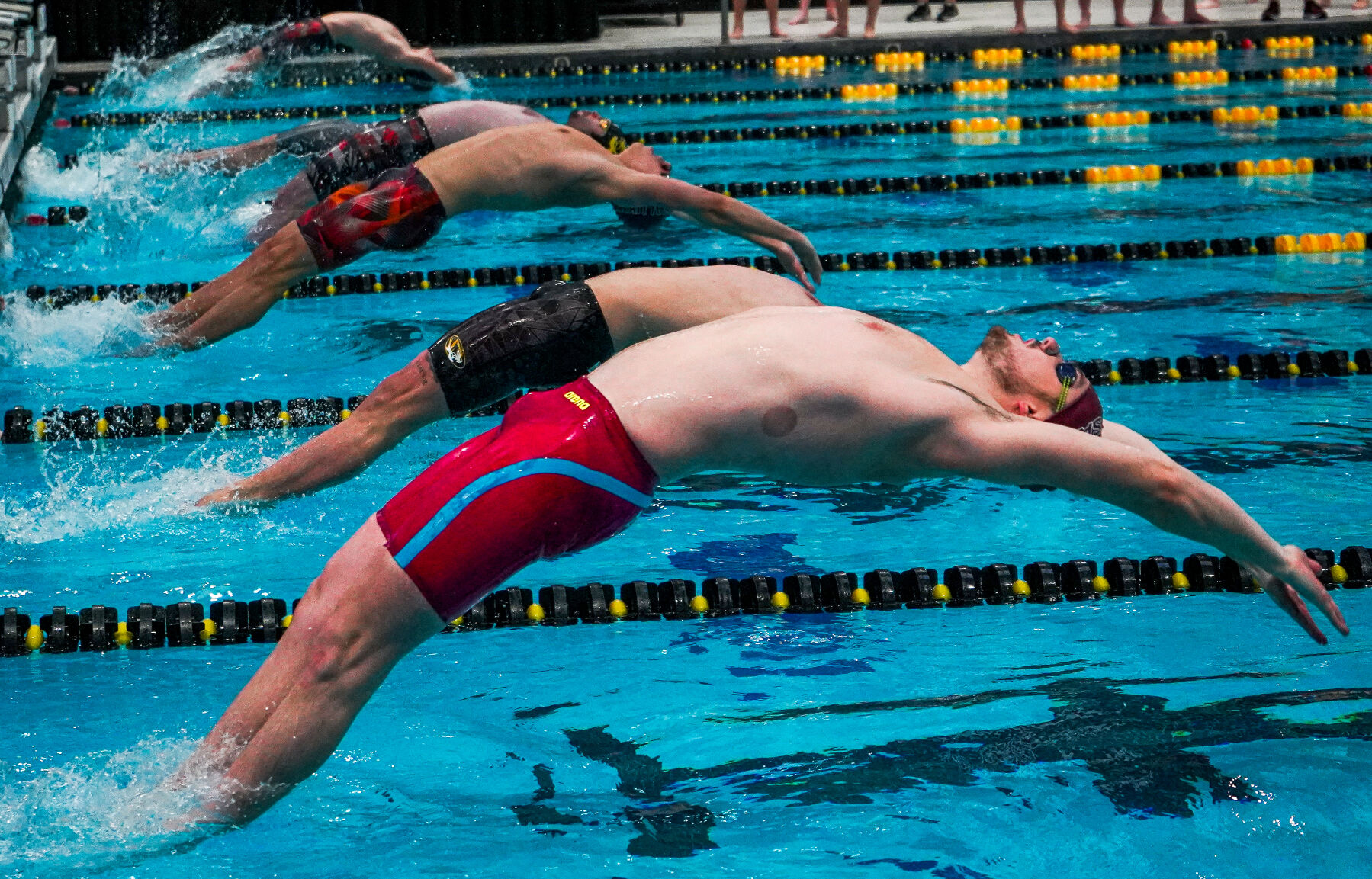 Swimmers launch off of the starting block.